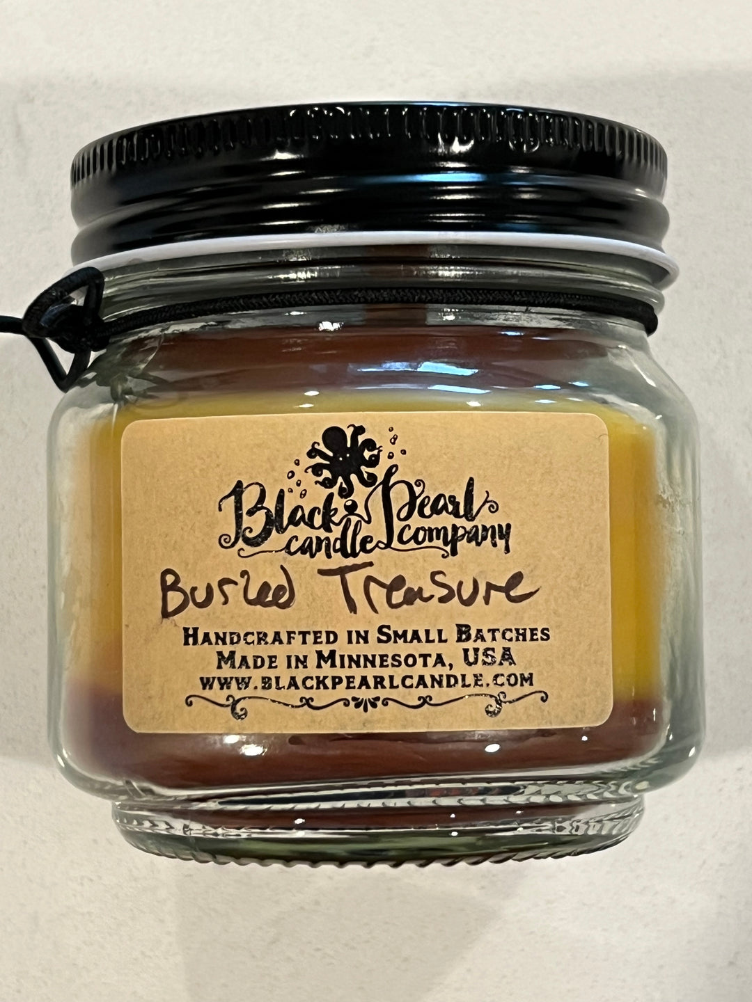 Buried Treasure scented candle in 8 oz mason jar with wood wick, soy-paraffin wax, and tropical fruit, rum, and spice fragrance