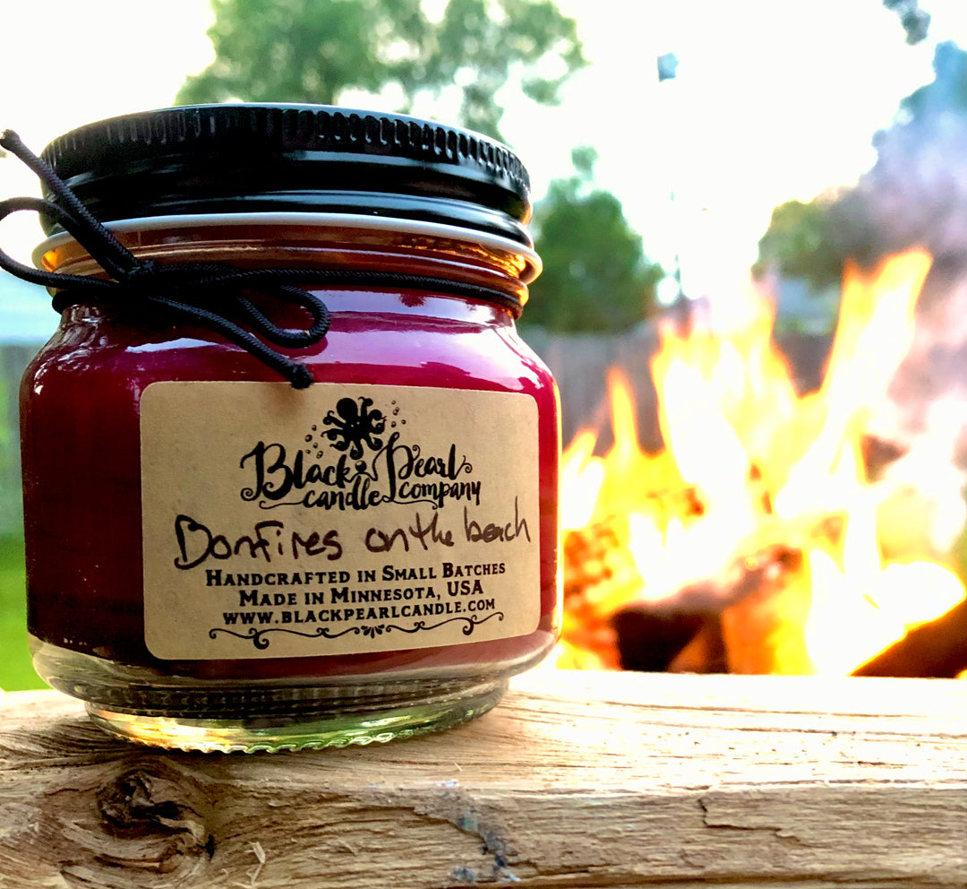 Candle jar from Black Pearl Candle Company by a campfire