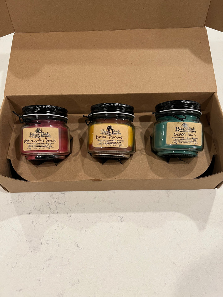 Monthly candle subscription box with three 8 oz mason jar candles featuring wood wicks and seasonal fragrance themes for holidays and seasons
